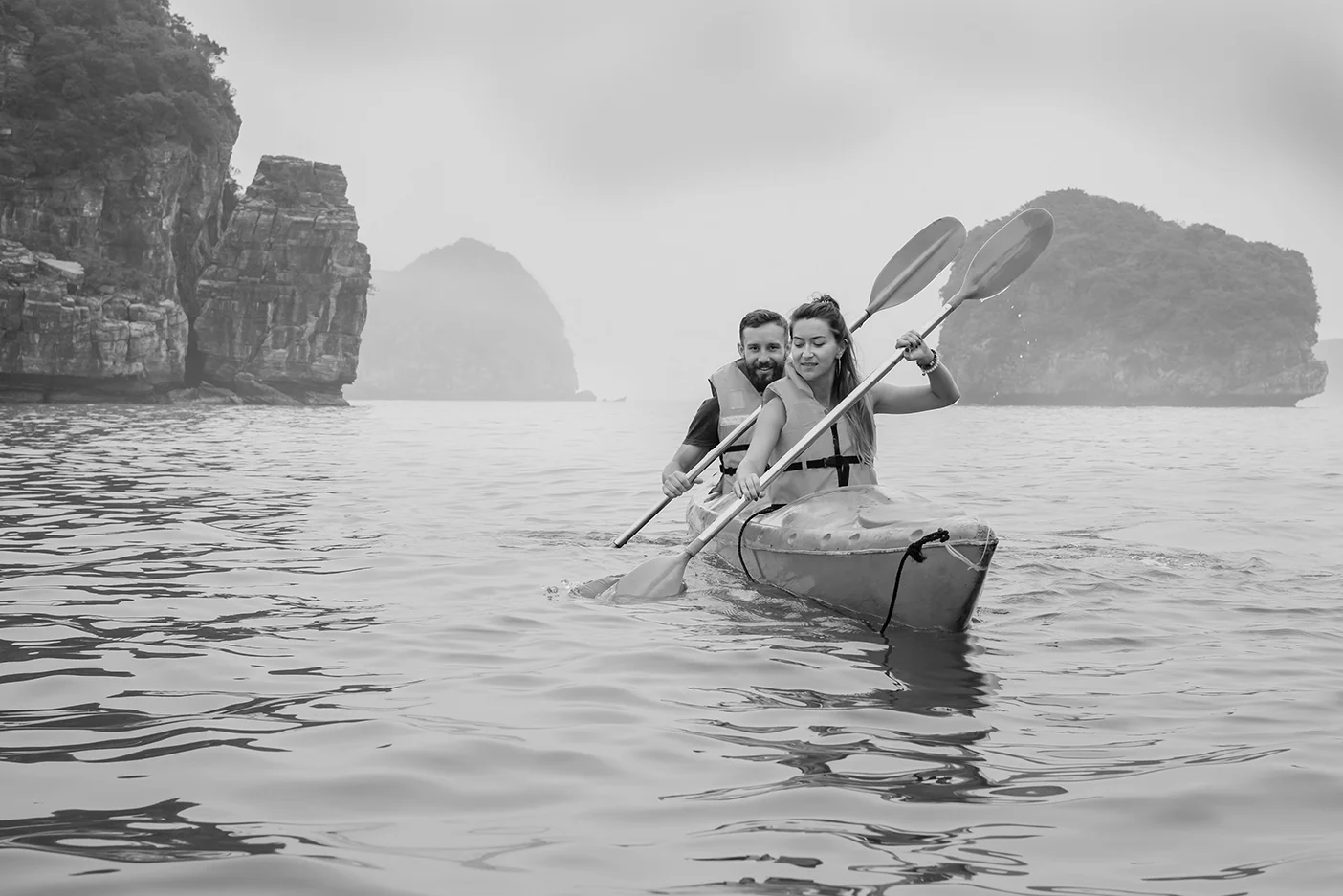 Couple d'aviron en kayak sur la mer brumeuse dans la baie d'Halong