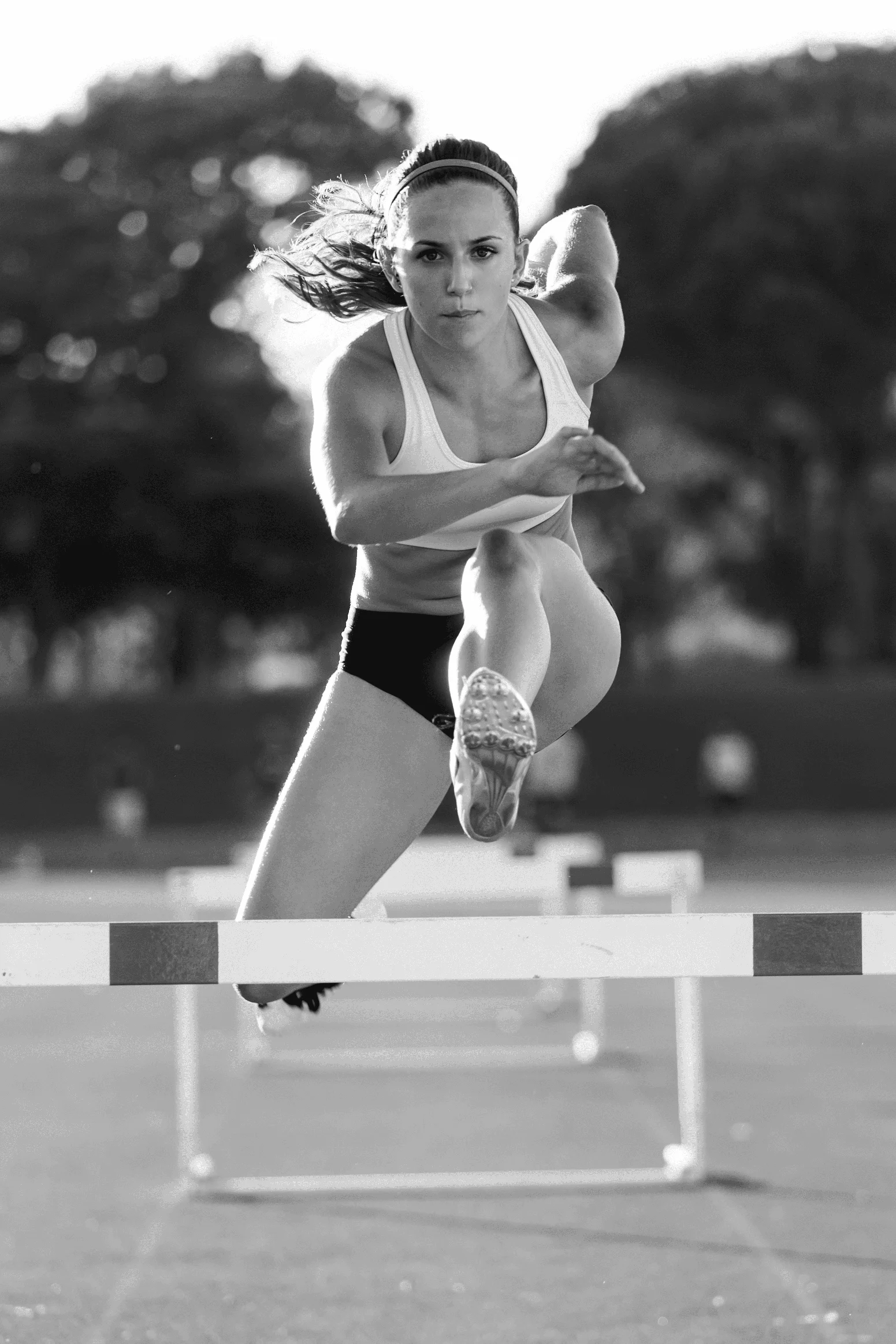 Jeune athlète sautant par-dessus un obstacle lors d'un entraînement sur une piste de course
