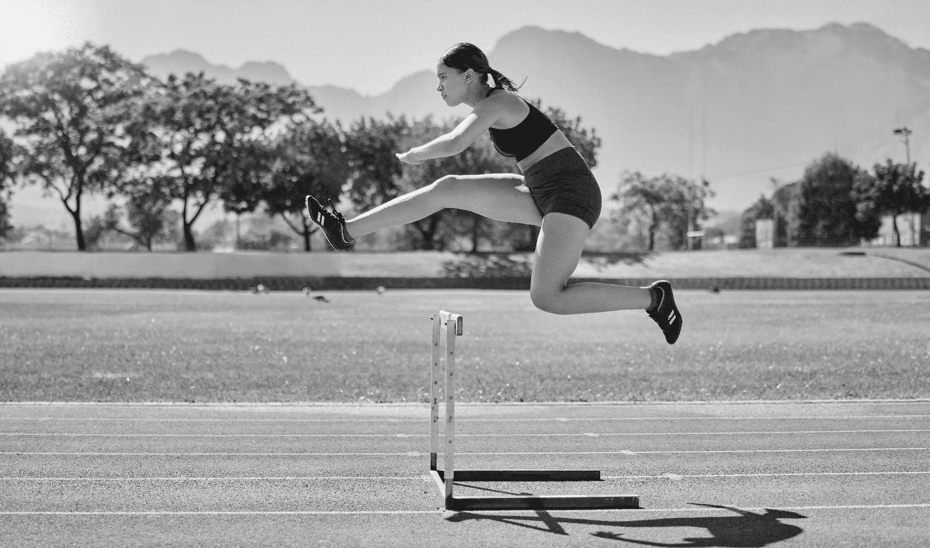 Sautez la haie, athlète et femme, pour la compétition, sur la piste et la course à pied pour la victoire, le bien-être et la santé