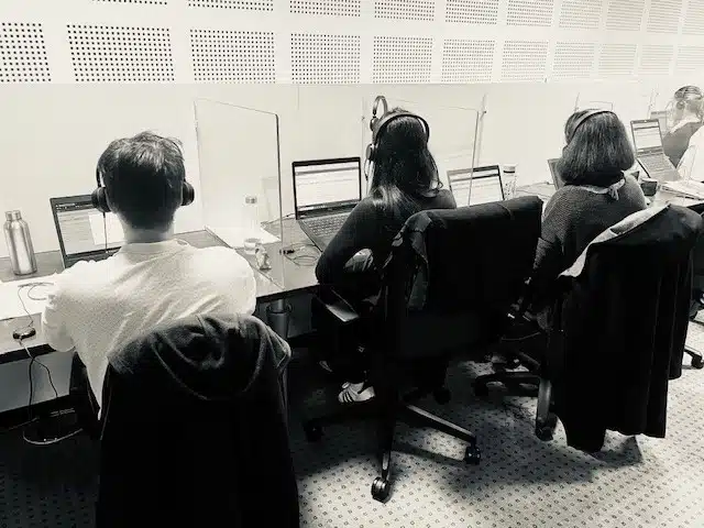 Trois enquêteurs téléphoniques travaillant avec des casques et ordinateurs portables dans le bureau d'études Evocime à Lorient.